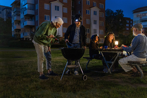 Grannar som har samlats runt en grill i ett bostadsområde.